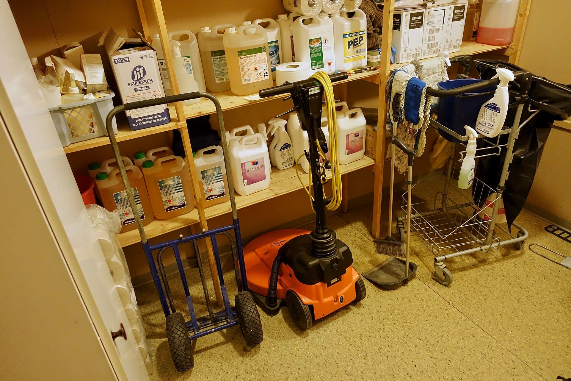 A school cleaner's cupboard with mop trolley, chemicals and a buffer